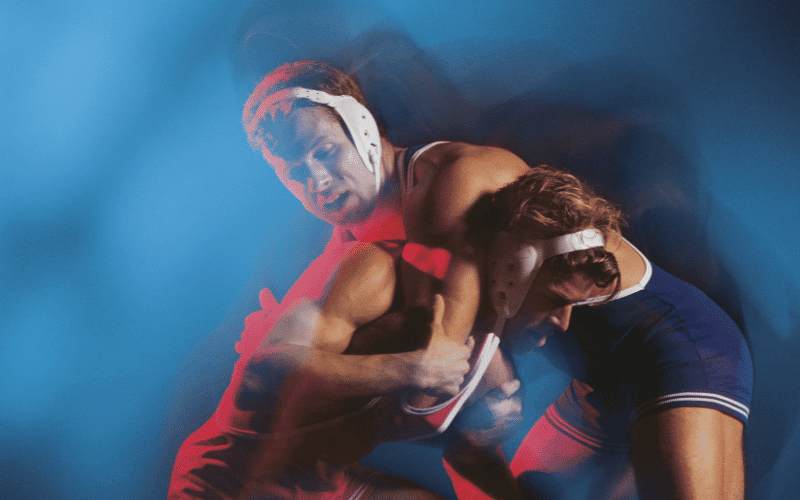 Two wrestlers demonstrating grappling techniques in a ring